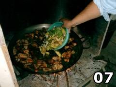 Foto di persona che aggiunge pomodoro nella paella valenciana