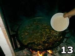 Foto di persona che aggiunge riso nella paella valenciana