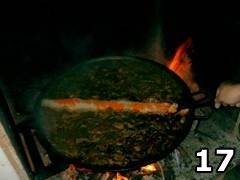 Foto di persona che aggiunge riso nella paella valenciana